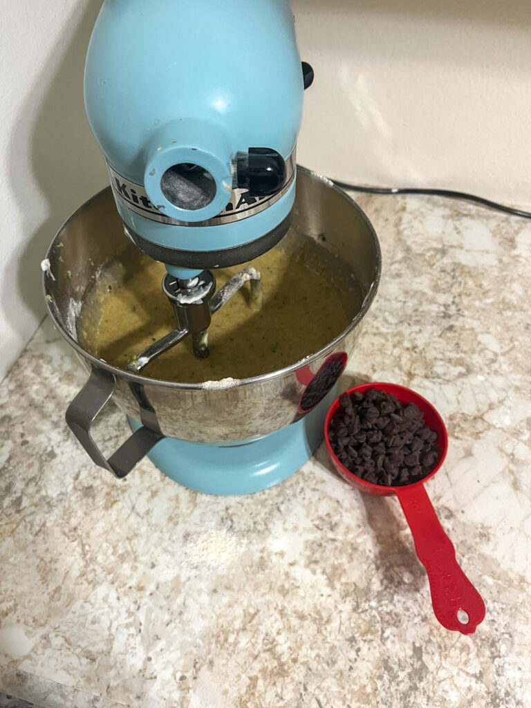 chocolate chips being poured in zucchini muffin batter