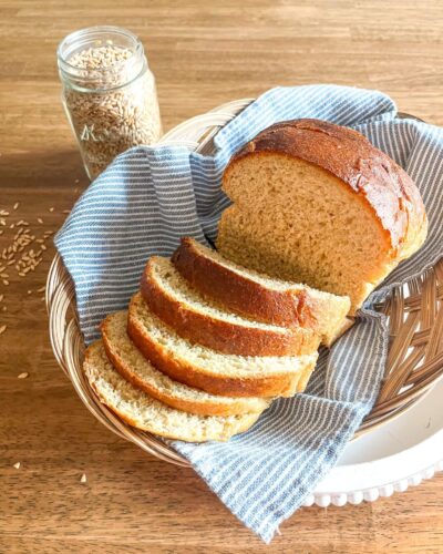 Fresh milled flour bread on a blue ktichen napkin inside a basket. Jar of wheat  berries in the background.