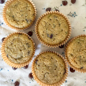 Close-up of healthy zucchini muffins with chocolate chips scattered on a floral kitchen towel