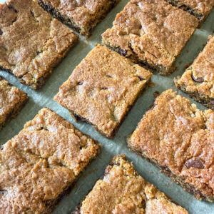 Close up sideways view of einkorn chocolate chip cookie bars on top of parchment paper.